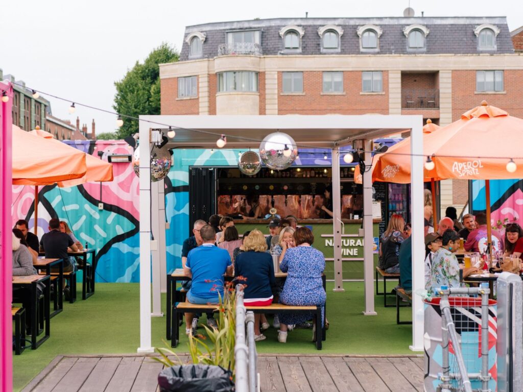 A photo of people sat at tables outside under a disco ball