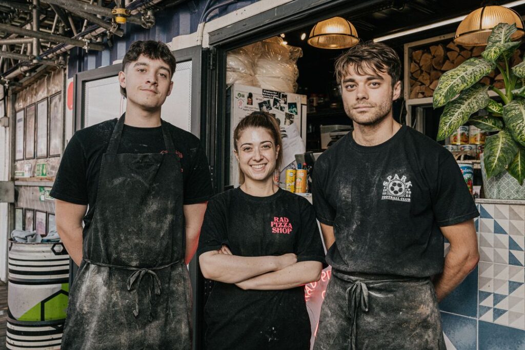 Two men and a woman outside Rad Pizza Shop