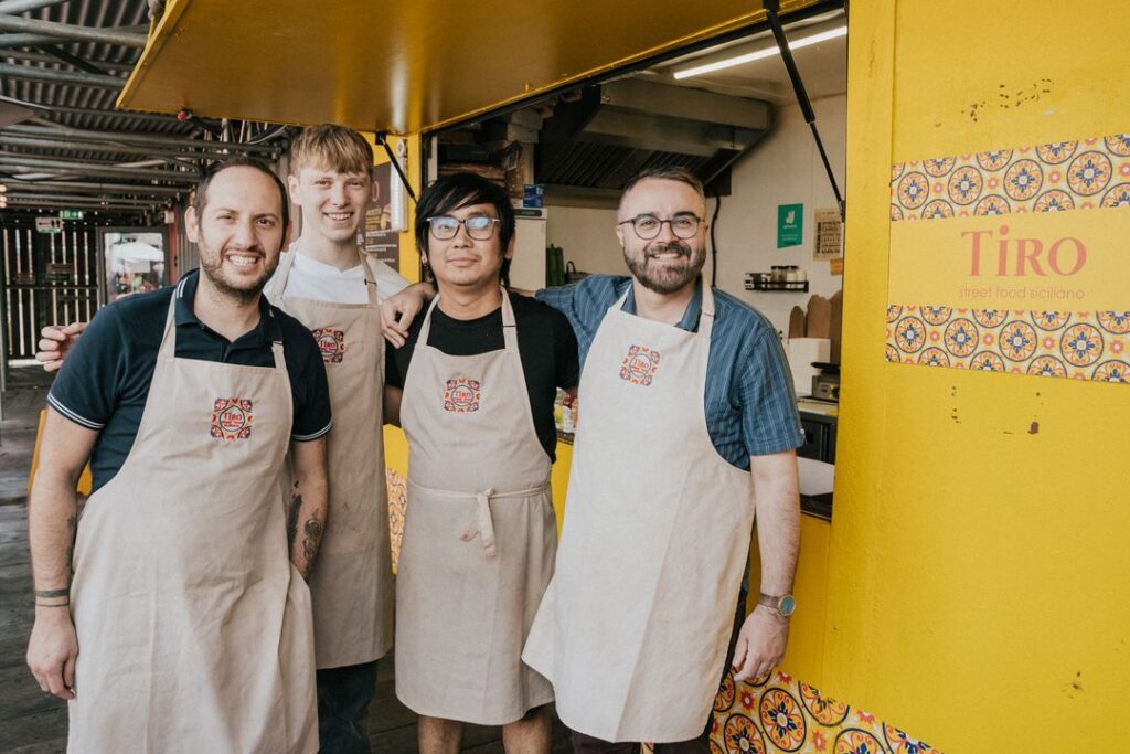 A photo of four men outside of Tiro
