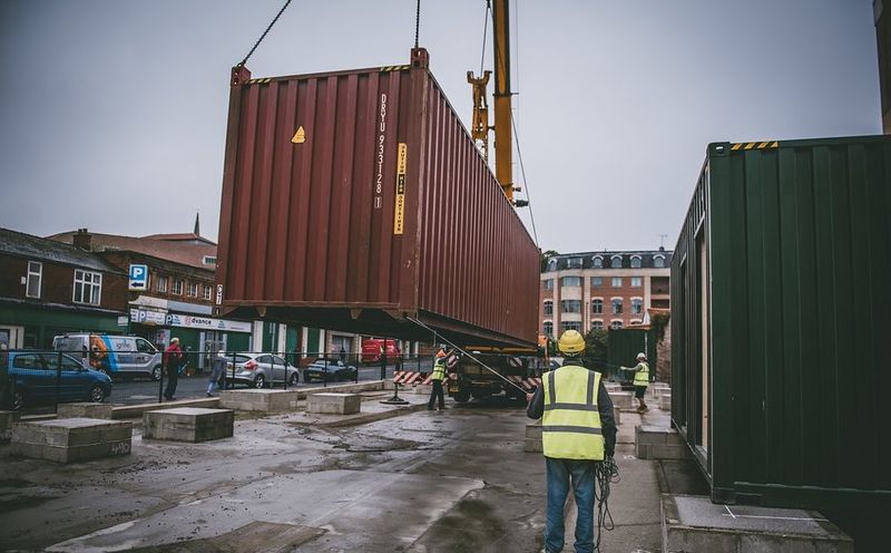 The first container being lowered via a crane onto the site
