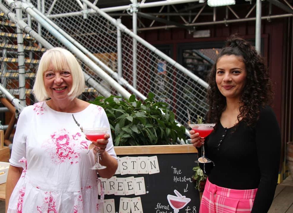Two woman at the bottom of a staircase holding cocktails