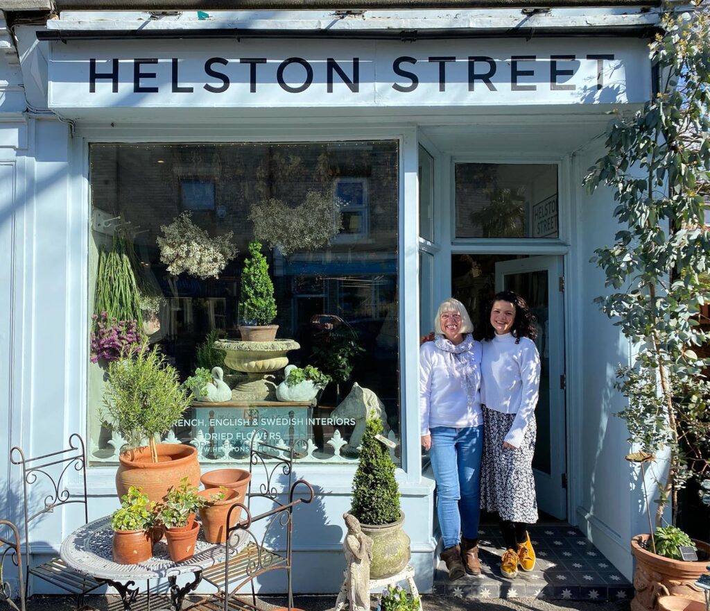 Two women outside a store with the sign "Helston Street"