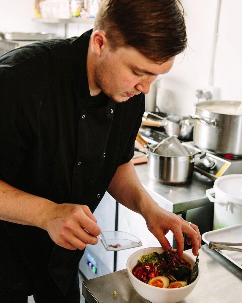 A photo of a man filling a bowl with salad