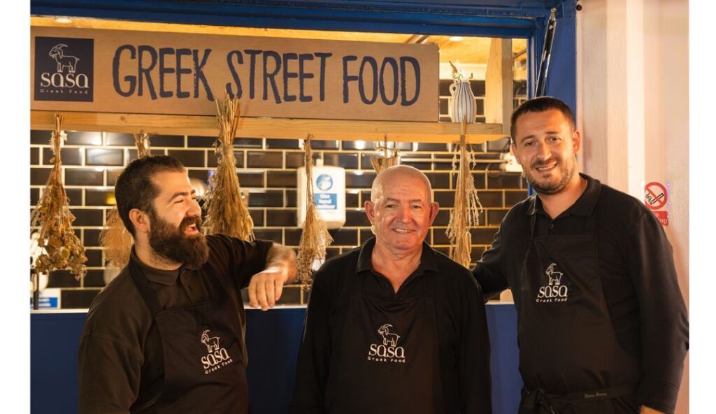 Three men stood outside Sasa Greek Street Food wearing aprons