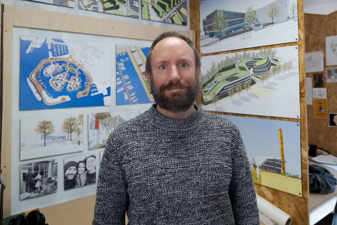 A photo of David in front of drawings of buildings
