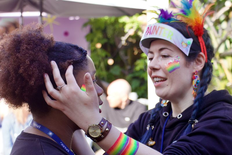 Two women doing face paint before joining the York Pride parade