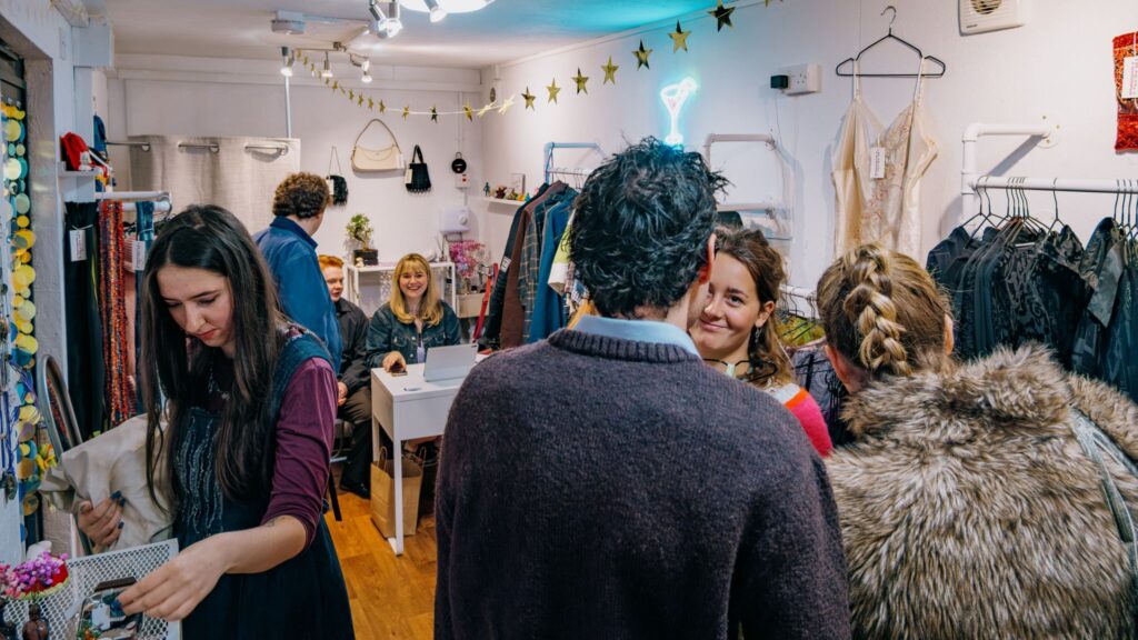 A group of people chatting and looking at clothing in a second-hand clothing store inside SPARK.