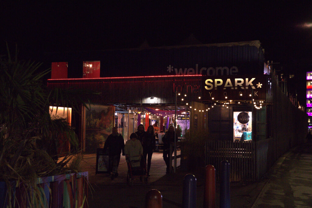 A photo of the front entrance of SPARK. It's night time and the logo glows.